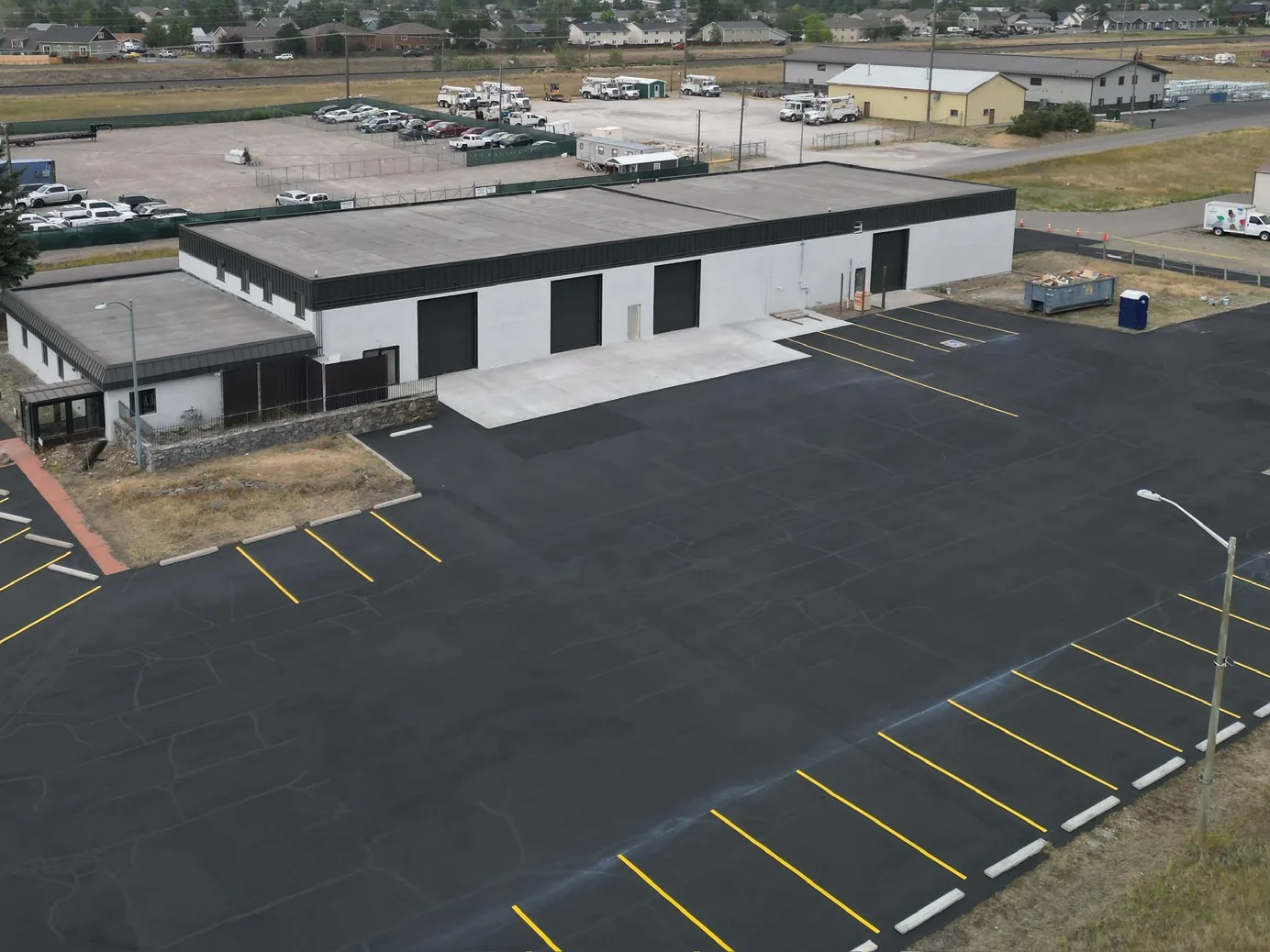 Aerial view of a finished commercial building with a new striped parking lot, commercial new construction