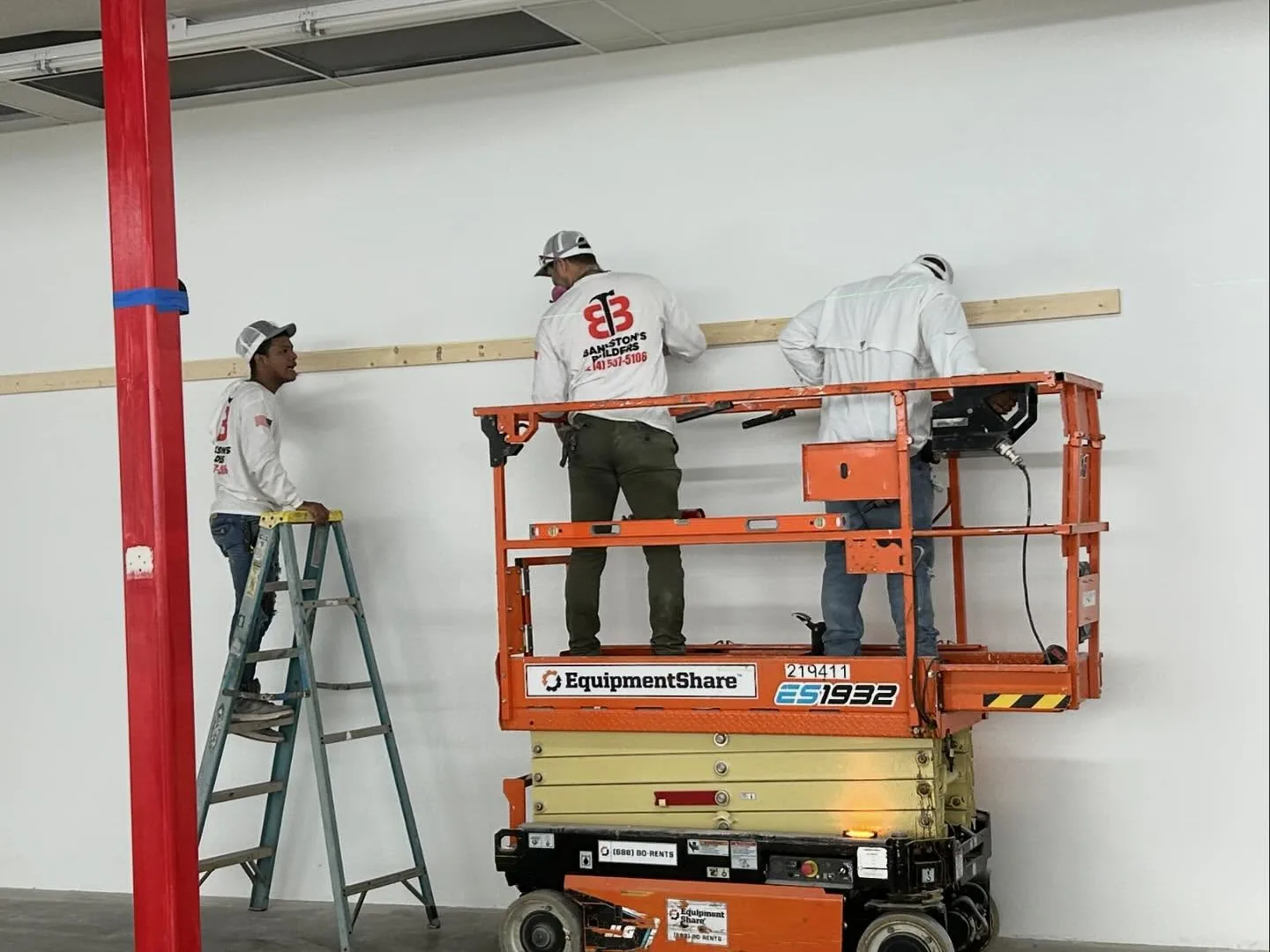 Crew on a scissor lift installing trim in a retail space, commercial tenant finish out