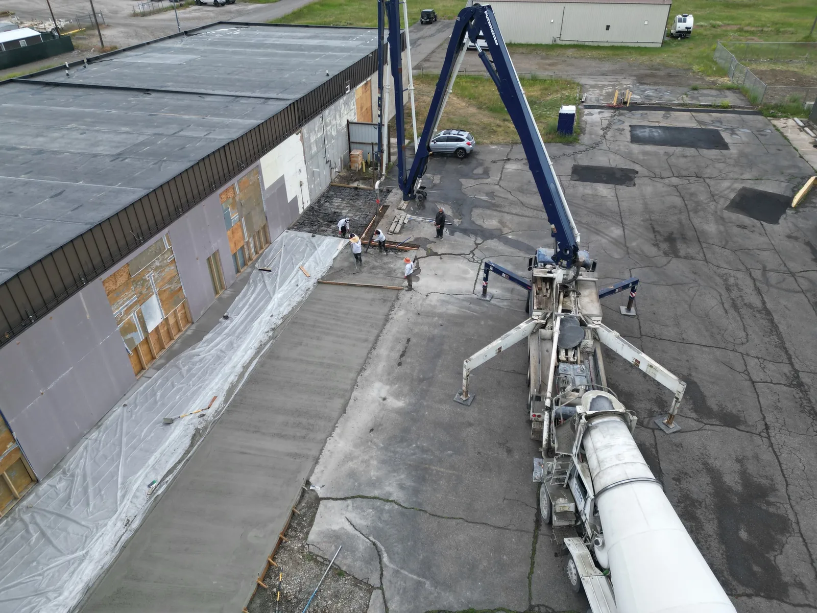 Concrete pump boom placing a slab beside a commercial building, concrete work
