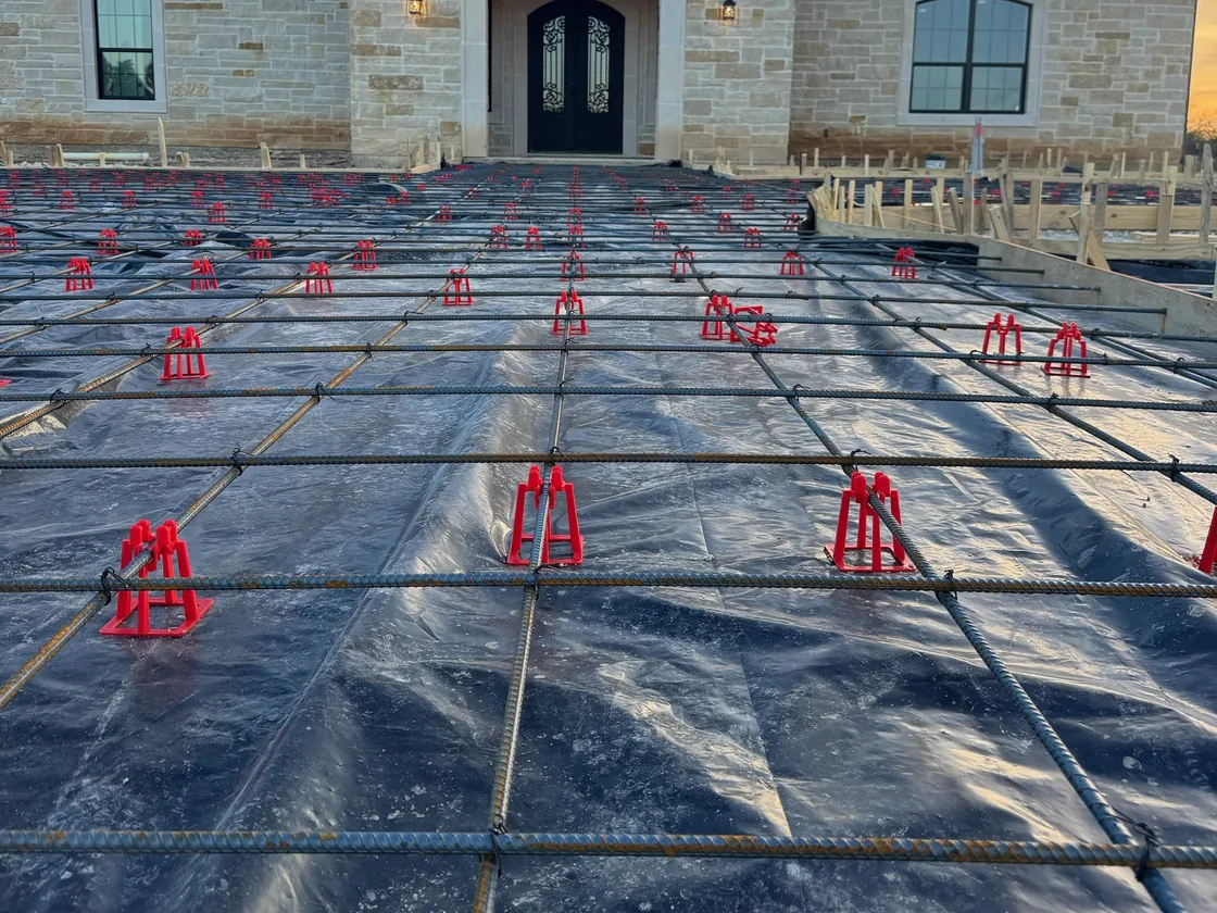 Rebar set on chairs over a vapor barrier before a slab pour, concrete work
