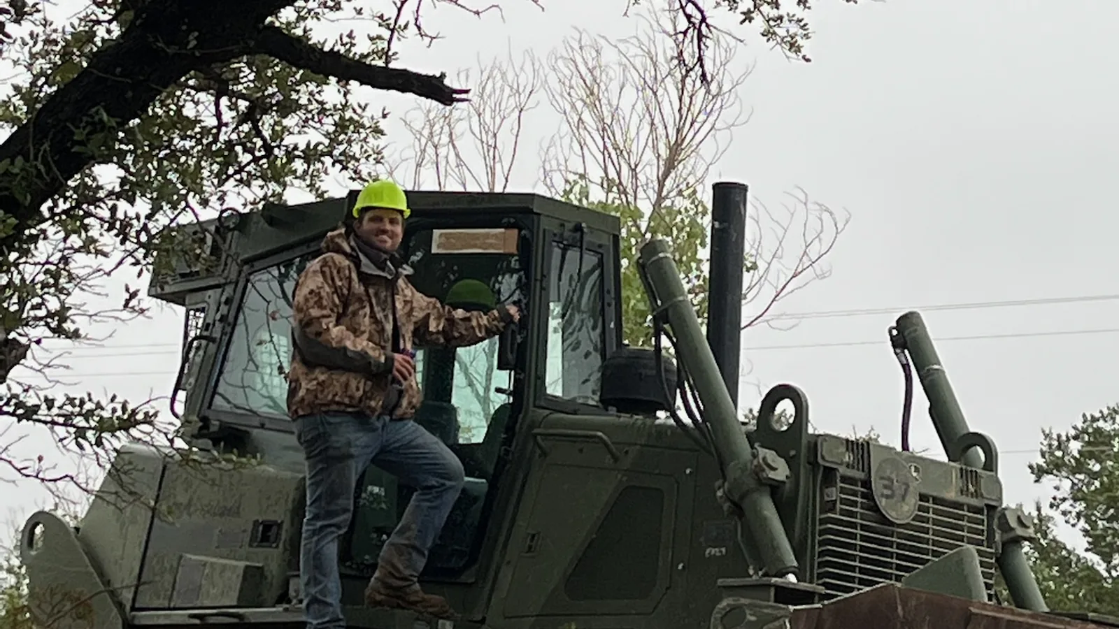 Dozer with its operator under a large oak