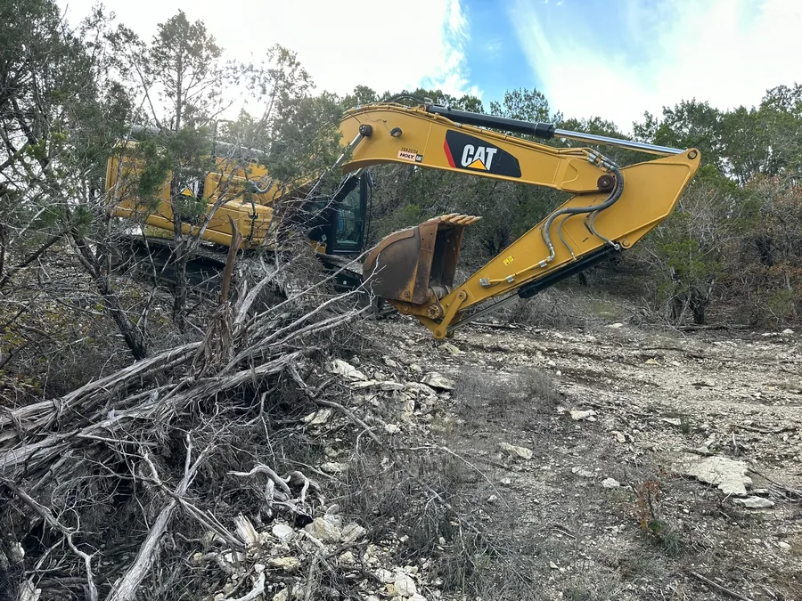 Excavator clearing brush and trees off a tract, land clearing