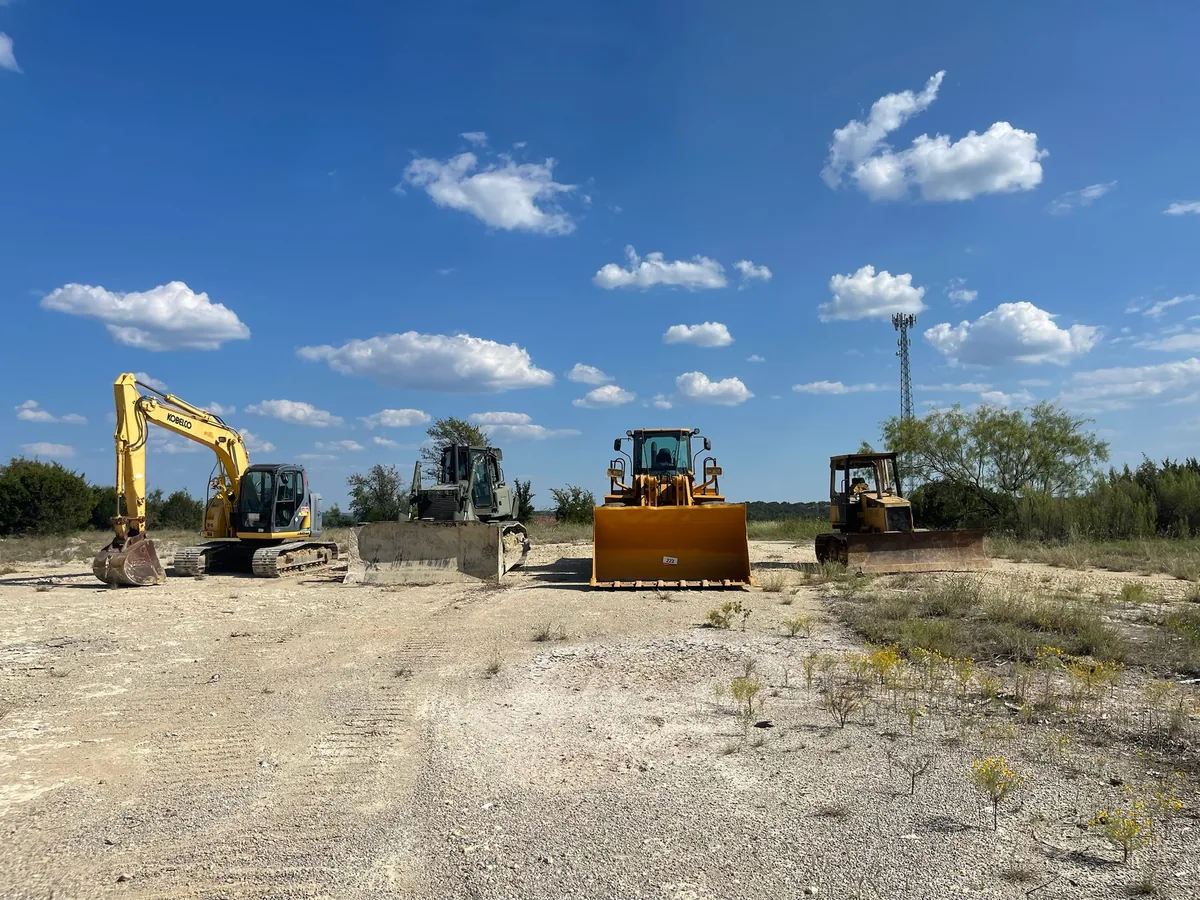 Excavator, dozers and a wheel loader on graded caliche ground, land grading