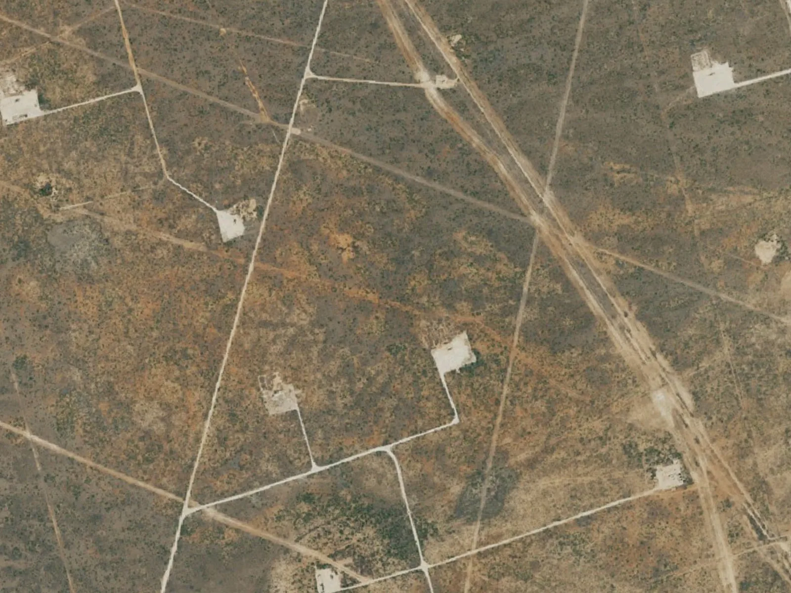 Aerial view of lease roads linking well pads on flat land, oilfield construction