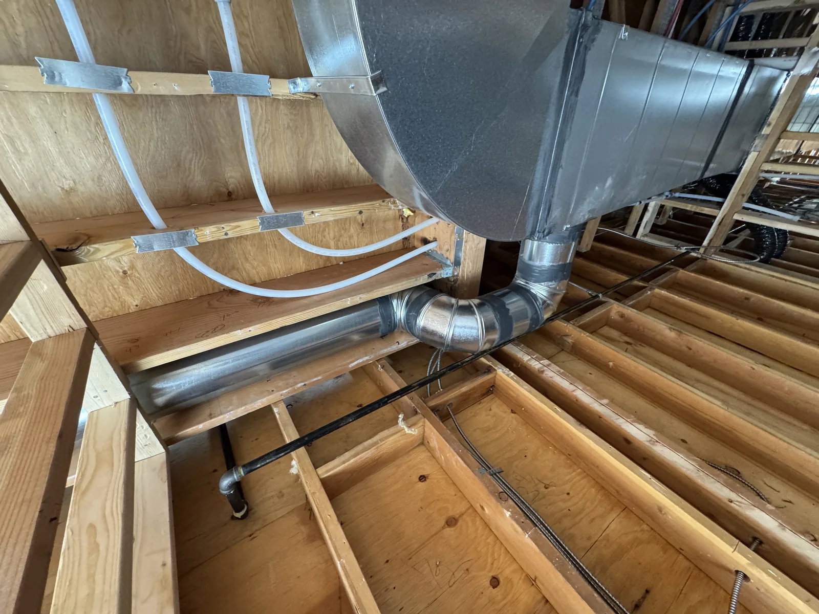 Duct trunk, water lines and a gas line run through the ceiling framing, commercial construction