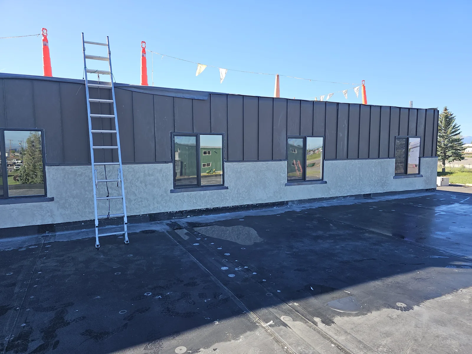 New membrane roof on a flat roof below a wall of new windows, commercial construction