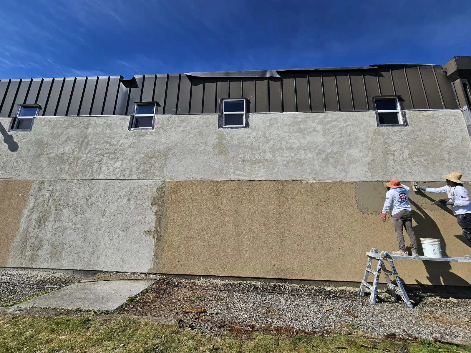 Crew troweling new stucco onto the exterior wall, commercial construction