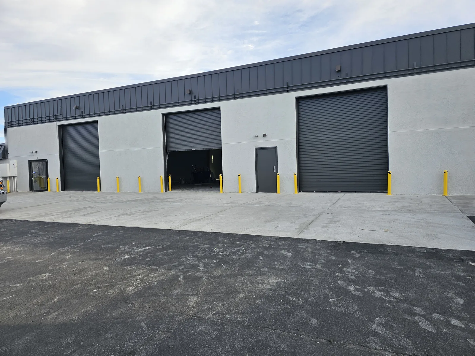 Finished building with new overhead doors, bollards and a concrete apron, commercial construction
