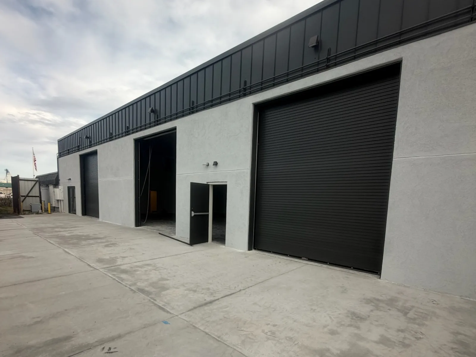 Rebuilt exterior wall with new stucco, overhead doors and a concrete apron, commercial construction