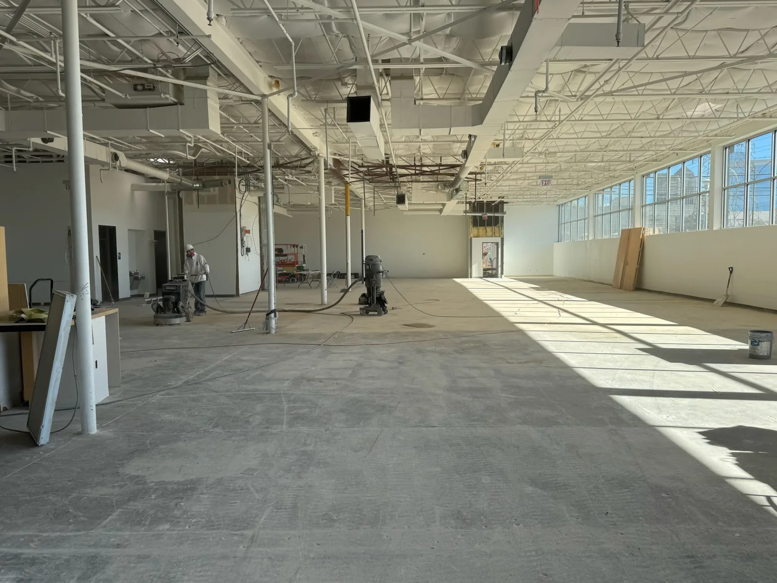 Open commercial shell with a crew grinding the concrete floor, commercial construction