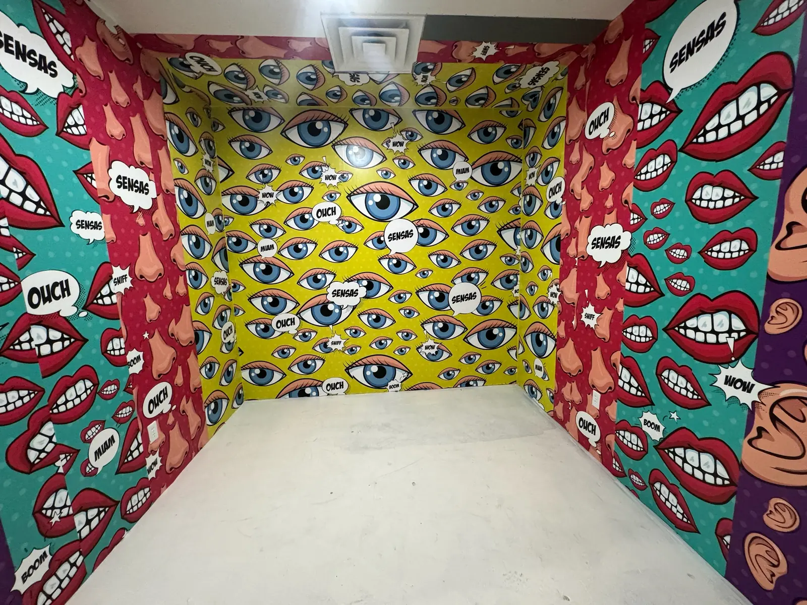 Small room wrapped in pop art murals with SENSAS speech bubbles, commercial construction