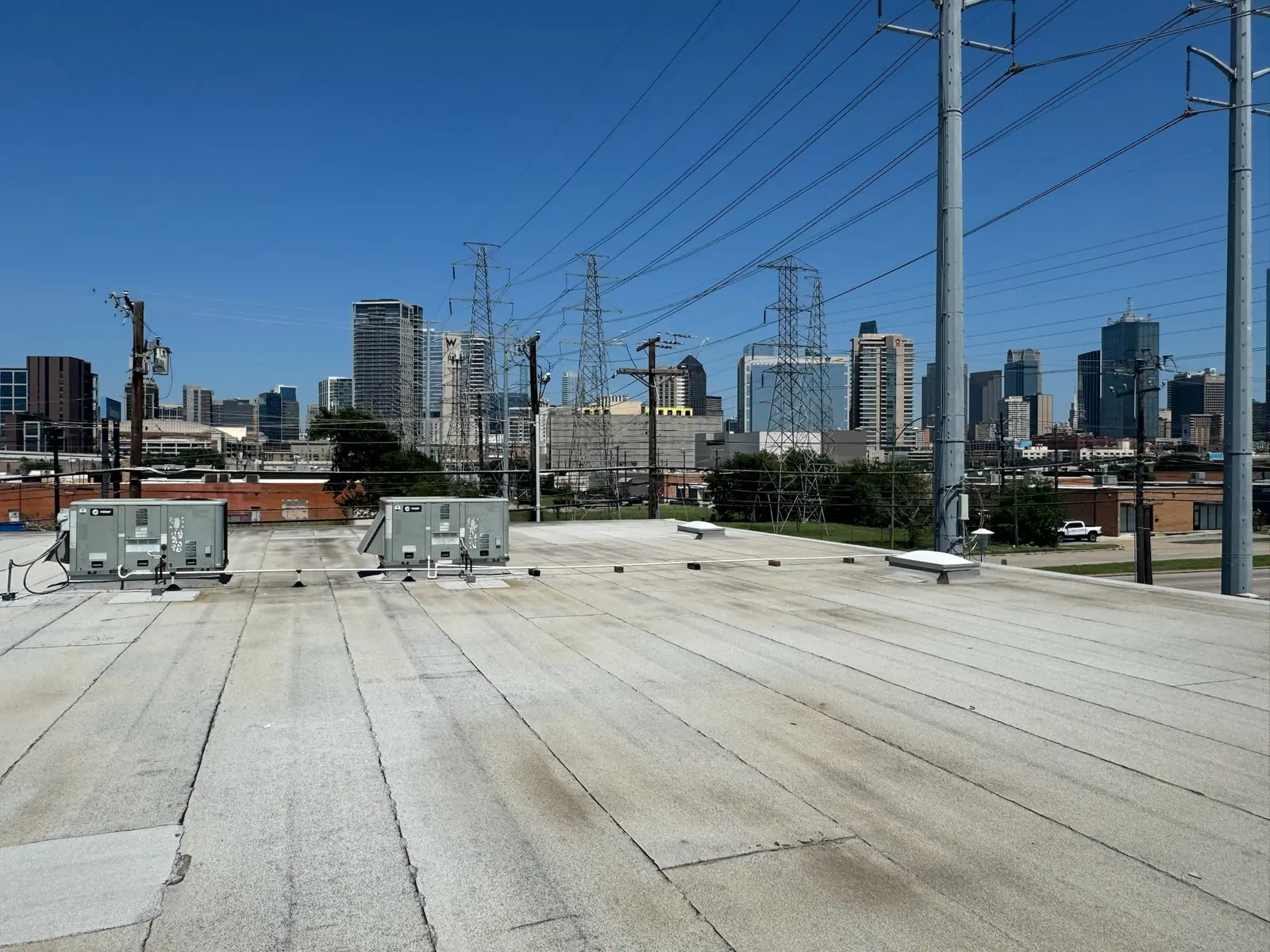 Rooftop air conditioning units with the downtown Dallas skyline behind, commercial construction