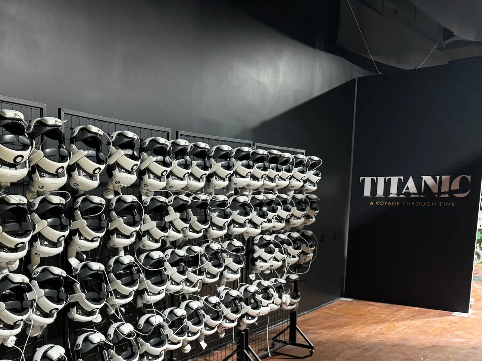 Racks of VR headsets beside a TITANIC A Voyage Through Time sign, commercial construction