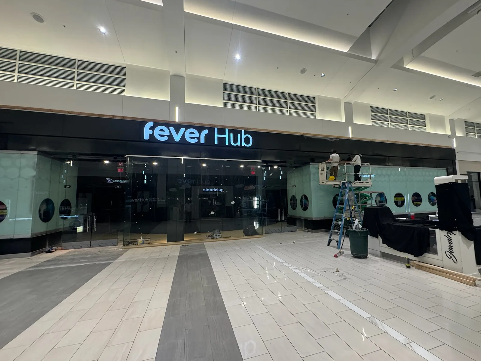 Fever Hub storefront with a crew on a scissor lift in a mall, commercial construction
