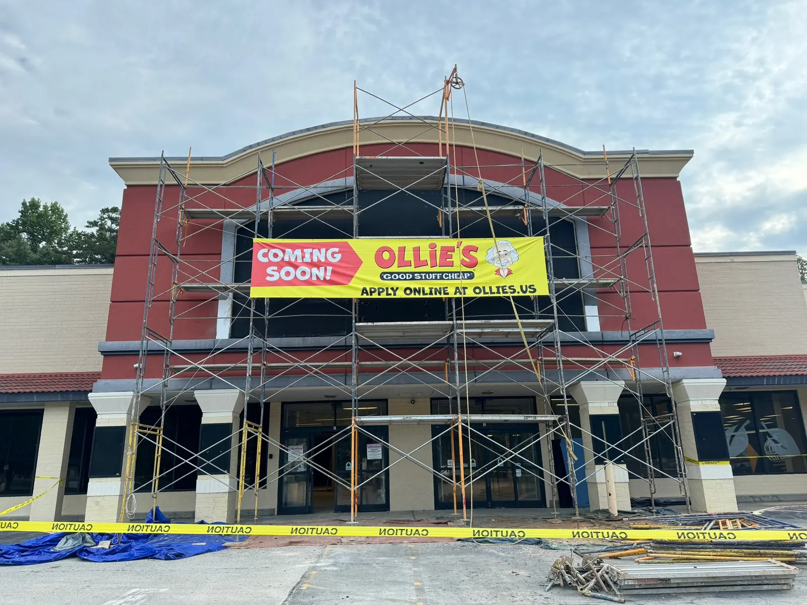 Old red store front under scaffolding with an Ollie's coming soon banner, commercial construction