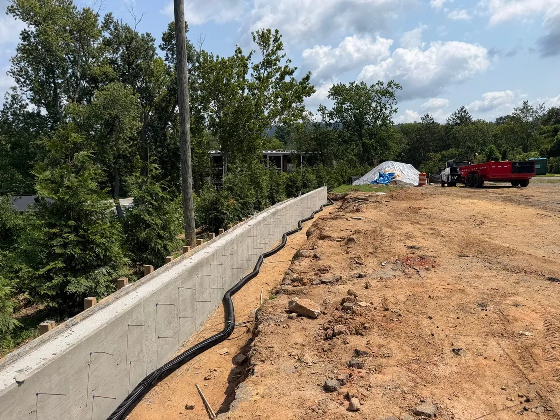 Drain pipe laid behind a new poured concrete retaining wall before backfill, retaining walls