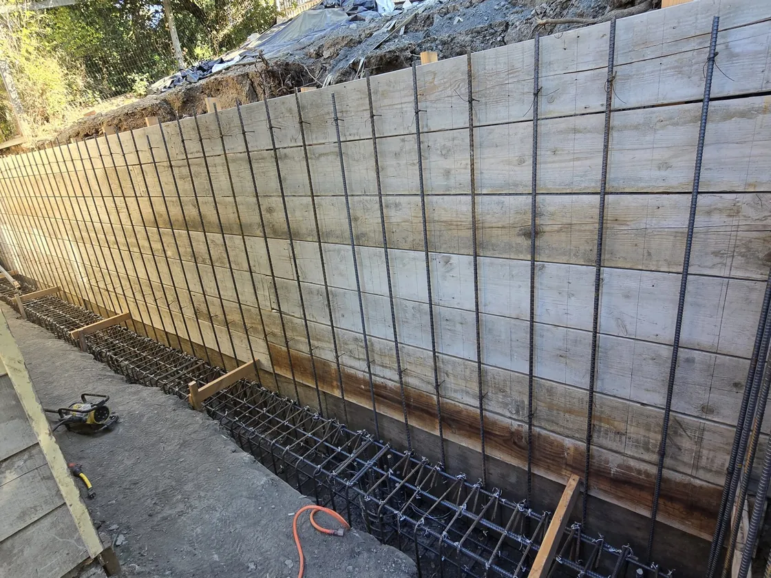 Wall forms, rebar and a footing cage set for a poured concrete retaining wall, retaining walls