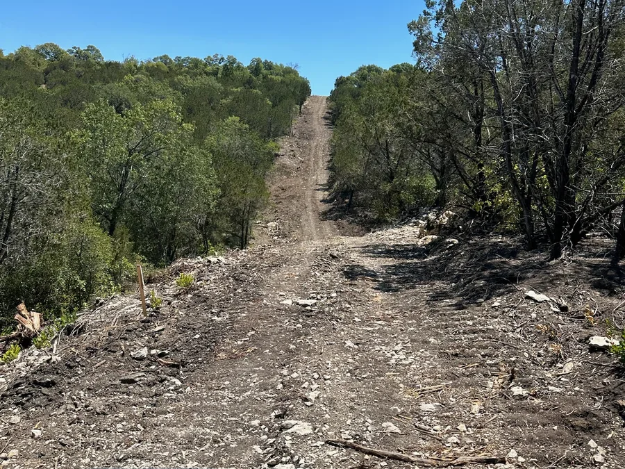 Freshly cut road through cedar and oak on a ranch, road building