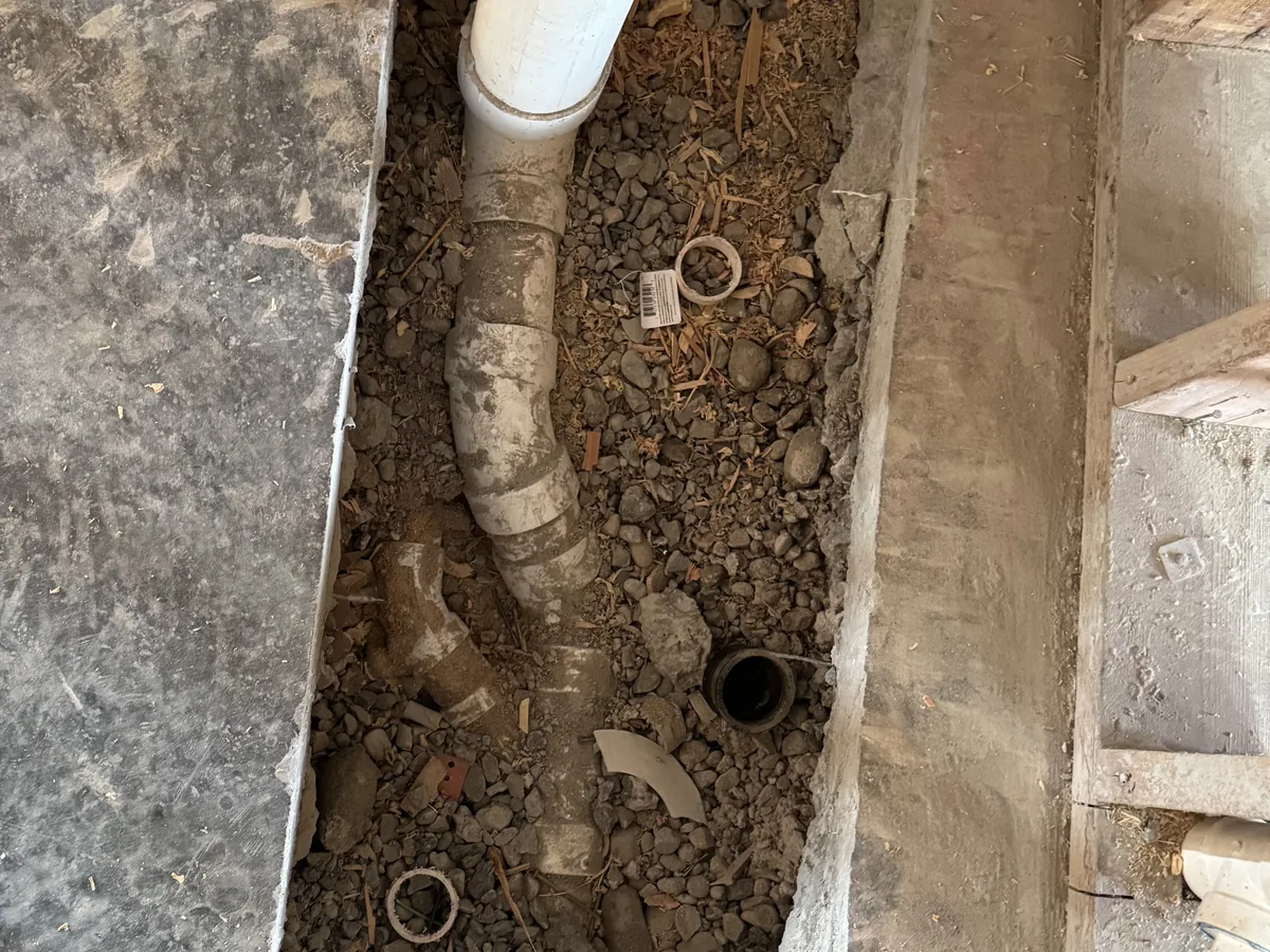 Trench cut through a concrete floor with new PVC pipe and fittings, utility trenching